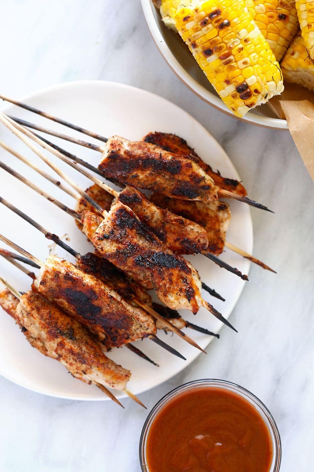 These BBQ Chicken Skewers are the perfect summer meal! Grab some skewers, BBQ sauce, and your favorite BBQ side dish and let's grill! Chicken Skewers on a plate.