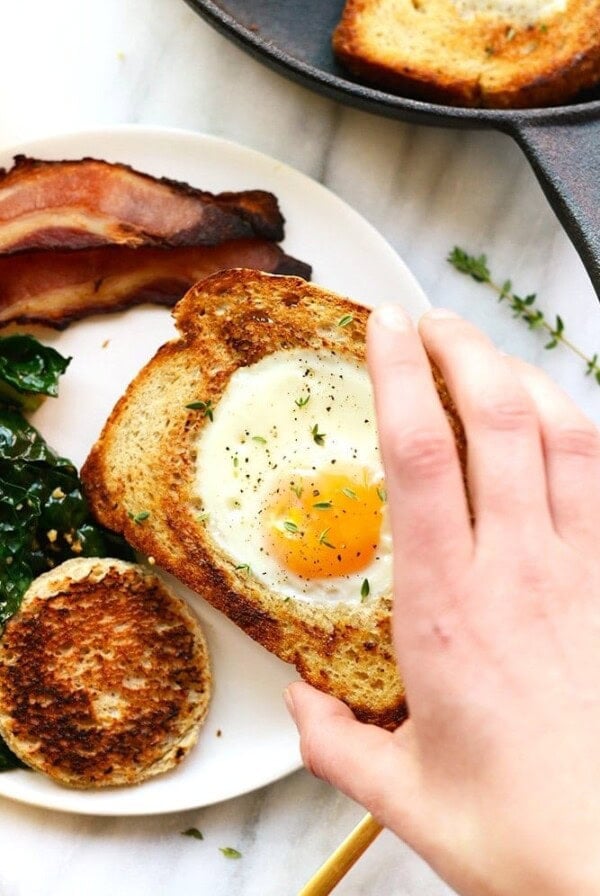 a person is making egg in a frame with bacon and greens.