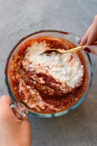 A person pouring sauce onto a Naked Spinach Quinoa Lasagna Casserole.