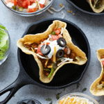 A group of tacos in a black skillet on a table.