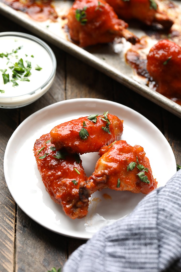 Make any game day or fun family gathering extra tasty with these Healthy Baked Chicken Wings. They’re perfectly crispy and tossed with a spicy + sweet buffalo sauce. Enjoy! 3 baked buffalo chicken wings on white plate