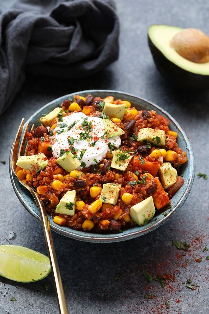 Incredible Mexican quinoa made in the slow cooker with tons of plant-based ingredients such as sweet potatoes and beans! Mexican quinoa in bowl with yogurt and sliced avocado
