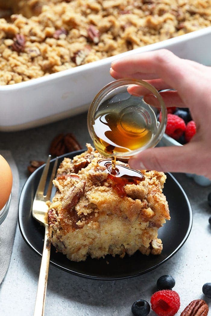 This overnight baked French toast recipe is made with maple syrup and pecans and is the perfect crowd-pleasing make-ahead breakfast! Pouring syrup on french toast bake