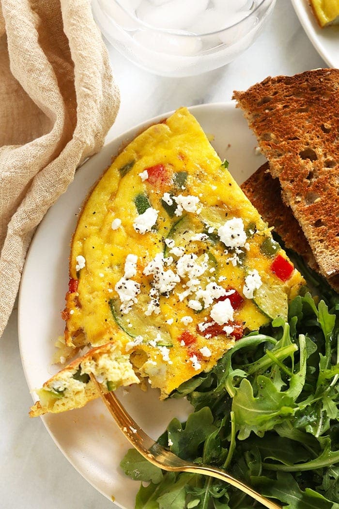 Do you have a bunch of veggies in the fridge? Make yourself a delicious and colorful vegetable frittata with farm fresh eggs and a sprinkle of parmesan cheese for a low-carb breakfast option! Frittata on a plate.