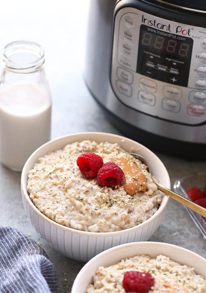 Make these Instant Pot Steel Cut Oats in a fraction of the time. They're creamy, served hot, and naturally gluten-free and vegan! Instant Pot steel cut oats in a bowl next to the Instant Pot.