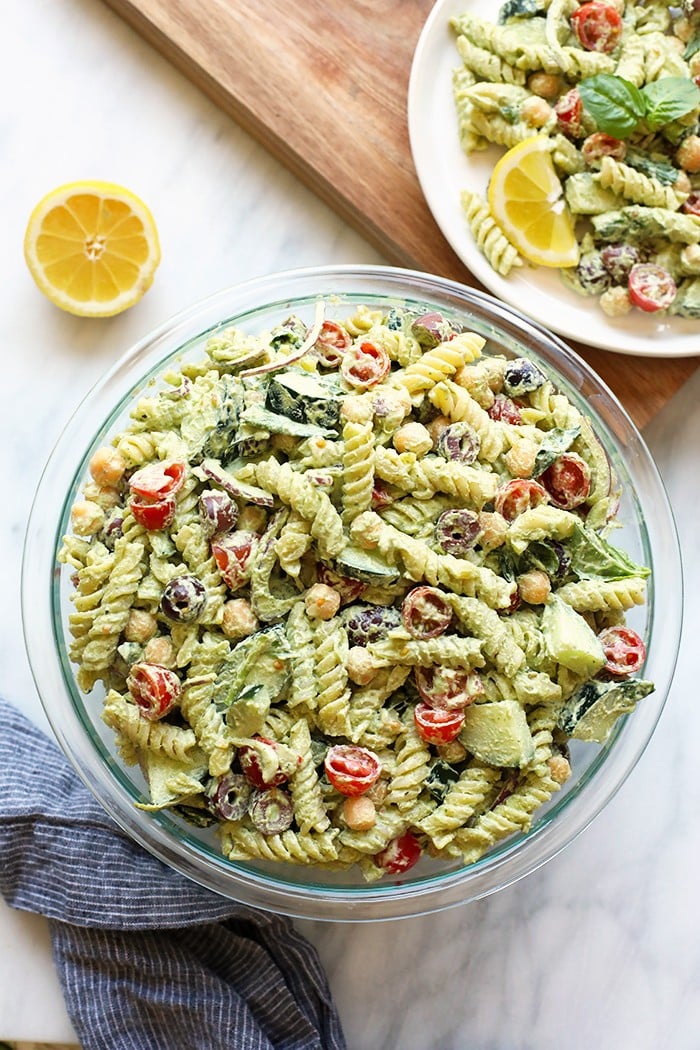 Are you ready for a mouthwatering vegan pasta salad recipe? This Creamy Greek Pasta Salad with Cashew Vegan Pesto packs in all the Greek flavor with a homemade cashew pesto sauce and is made with fresh, seasonal produce and your favorite pasta noodle. Vegan pasta salad in a bowl.