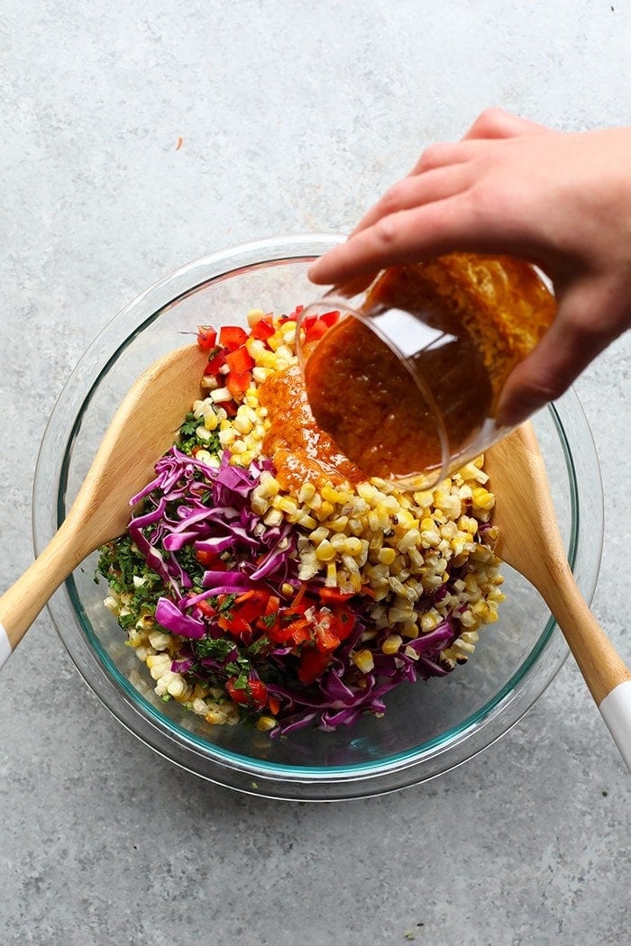 We love this Thai Chili Summer Corn Salad. It's made with grilled corn, carrots, red pepper, cabbage, and the most delicious vinaigrette! Make this grilled corn salad today. Corn salad ingredients in a bowl.