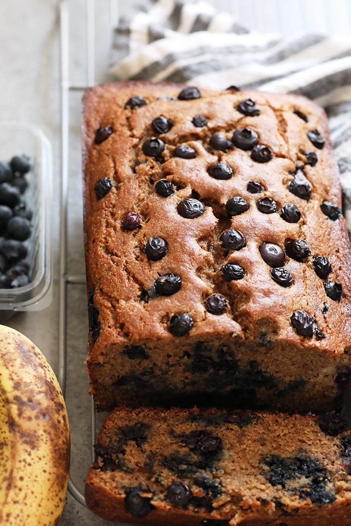 Perfectly moist blueberry banana bread made with whole grains, Greek yogurt, fresh blueberries, and maple syrup! Banana Bread on a cooling rack.