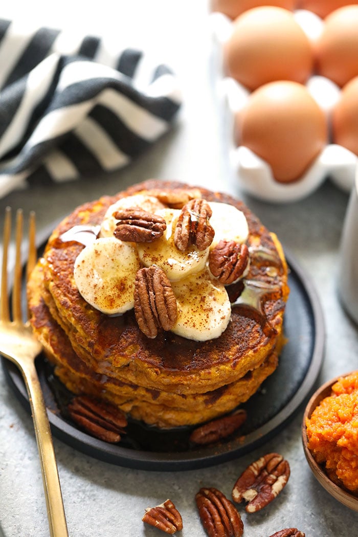 Start your day off right with these grain-free, pumpkin-packed, and oh so scrumptious Paleo Pumpkin Pancakes. These festive pancakes will spruce up your Fall breakfasts all season long. Whip up a batch today! Paleo pumpkin pancakes on a plate.