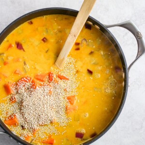 A steaming bowl of curry chicken soup with a wooden spoon in it.