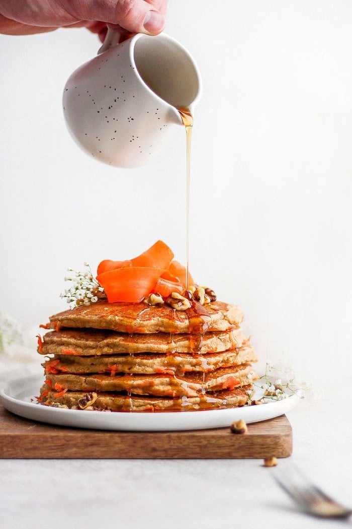 It's time to make the best gluten free pancakes you've ever tasted! Our carrot cake pancakes are made with ground oat flour, carrot cake spices, and freshly grated carrots. Whip up a batch for breakfast today or meal prep to enjoy throughout the week! healthy carrot cake pancakes on a plate