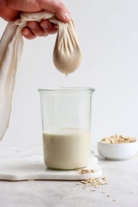 squeezing oat milk out of cheese cloth.