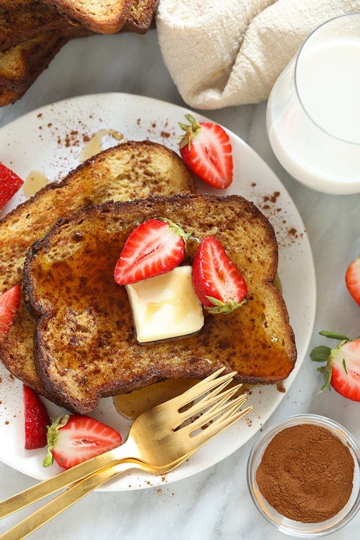 This Sheet Pan French Toast is the answer to your brunch dreams! It's ready to serve in under 30 minutes, and can easily be doubled to serve a crowd. Happy brunching! sheet pan french toast on a plate with strawberries