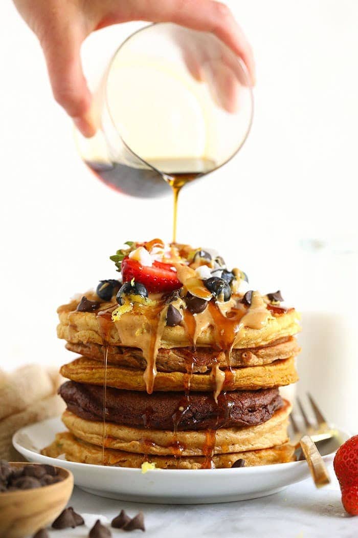 If you love pancakes, add this healthy pancake recipe to the list! This is our favorite pancake base recipe + 6 healthy pancake recipes you can make with it. Start flipping those flapjacks! Pouring syrup onto a stack of pancakes.