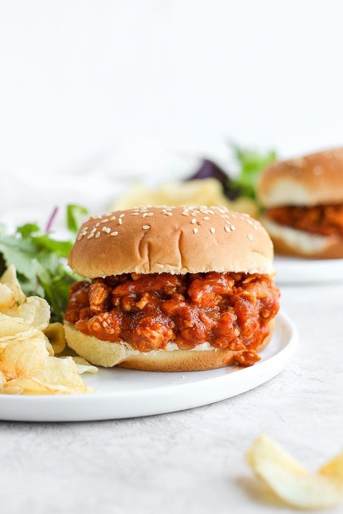 The perfectly savory and sweet Healthy Sloppy Joe Recipe is here! Made with ground chicken and a flavorful sauce packed with clean ingredients, these Sloppy Joes will not disappoint! healthy sloppy joe on a bun with chips