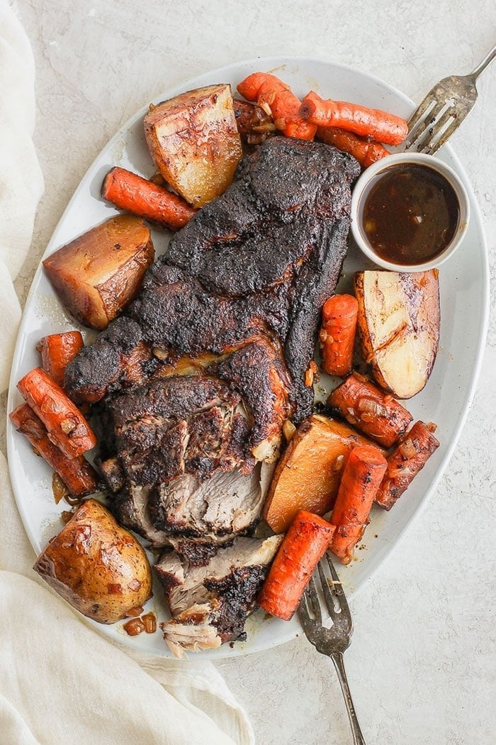 This slow cooker pork roast is fall off the bone delicious and all you have to do is throw everything in the slow cooker and you're golden. Make this crock pot pork roast for dinner this week; you'll have tons of leftovers! Pork roast on a platter with vegetables.