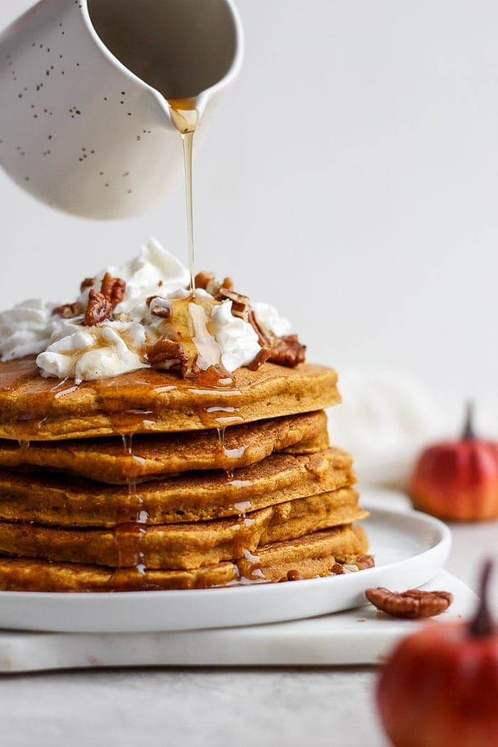 Pumpkin pancakes made from whole wheat flour, pumpkin puree, maple syrup, and pumpkin pie spice. A stack of these healthy pumpkin pancakes is going to make your tummy happy! Stack of pumpkin pancakes.