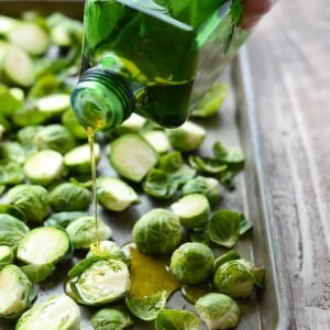 brussel sprouts being drizzled with olive oil