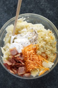 a bowl of potato salad with bacon, cheese and sour cream inspired by twice baked potatoes.