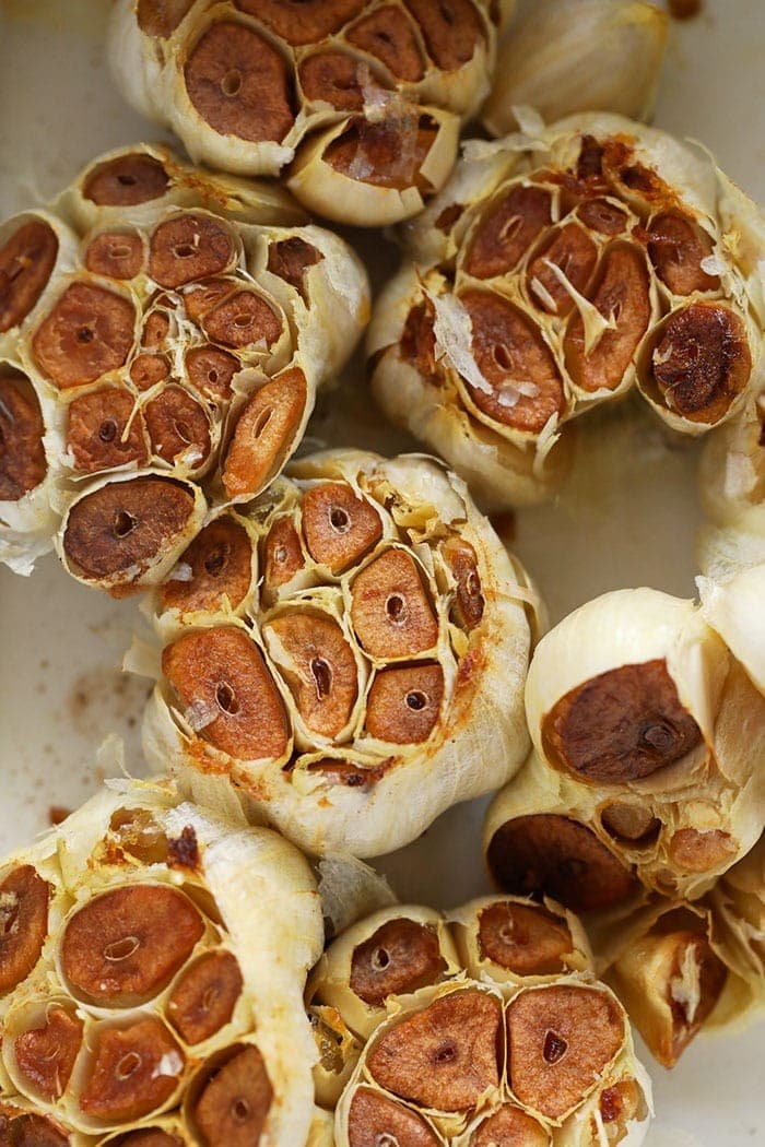 Making your own roasted garlic could not be easier! This tutorial will show you How to Roast Garlic in the oven in 4 simple steps, how to use it, as well as how to store it so you can always have delicious roasted garlic cloves on hand. roasted garlic cloves in a baking dish