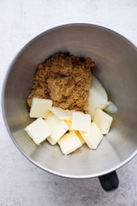 A mixing bowl with butter, sugar, and flour for gingersnap cookies.