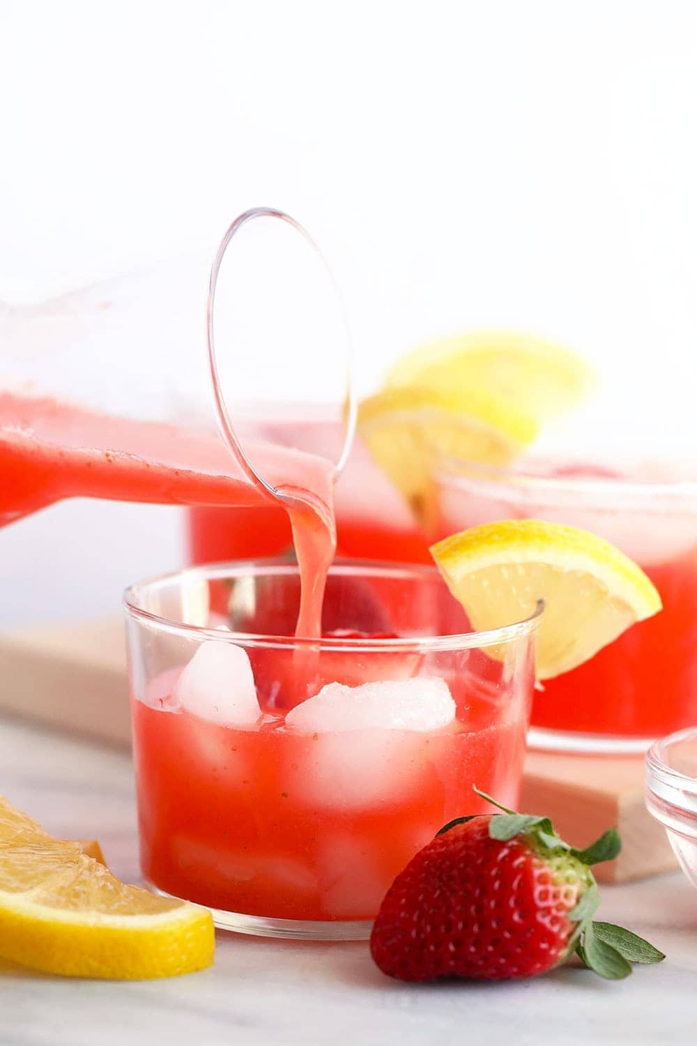 This Strawberry Vodka Lemonade is made with fresh strawberry puree, fresh squeezed lemons and a honey simple syrup, plus vodka, of course! Get ready for your new favorite homemade cocktail. strawberry vodka lemonade being poured in a glass