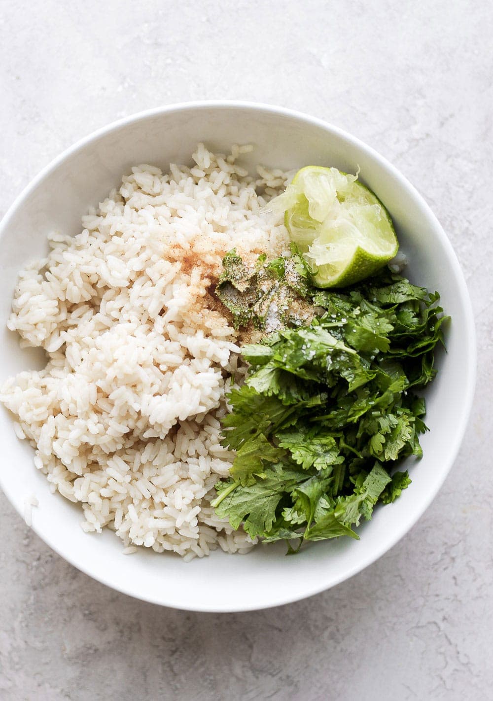 rice ready to be mixed with cilantro and lime in a bowl