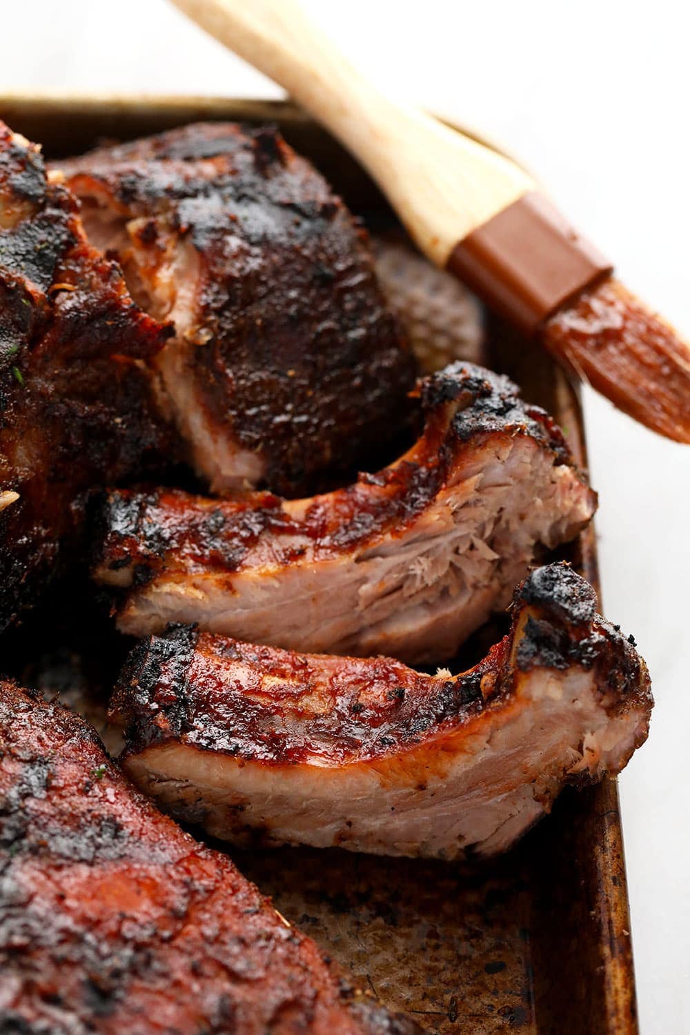 Incredible 24 hour sous vide ribs made with a smokey dry rub and caramelized to perfection on the grill! Sous Vide Ribs on a baking sheet with sauce brush