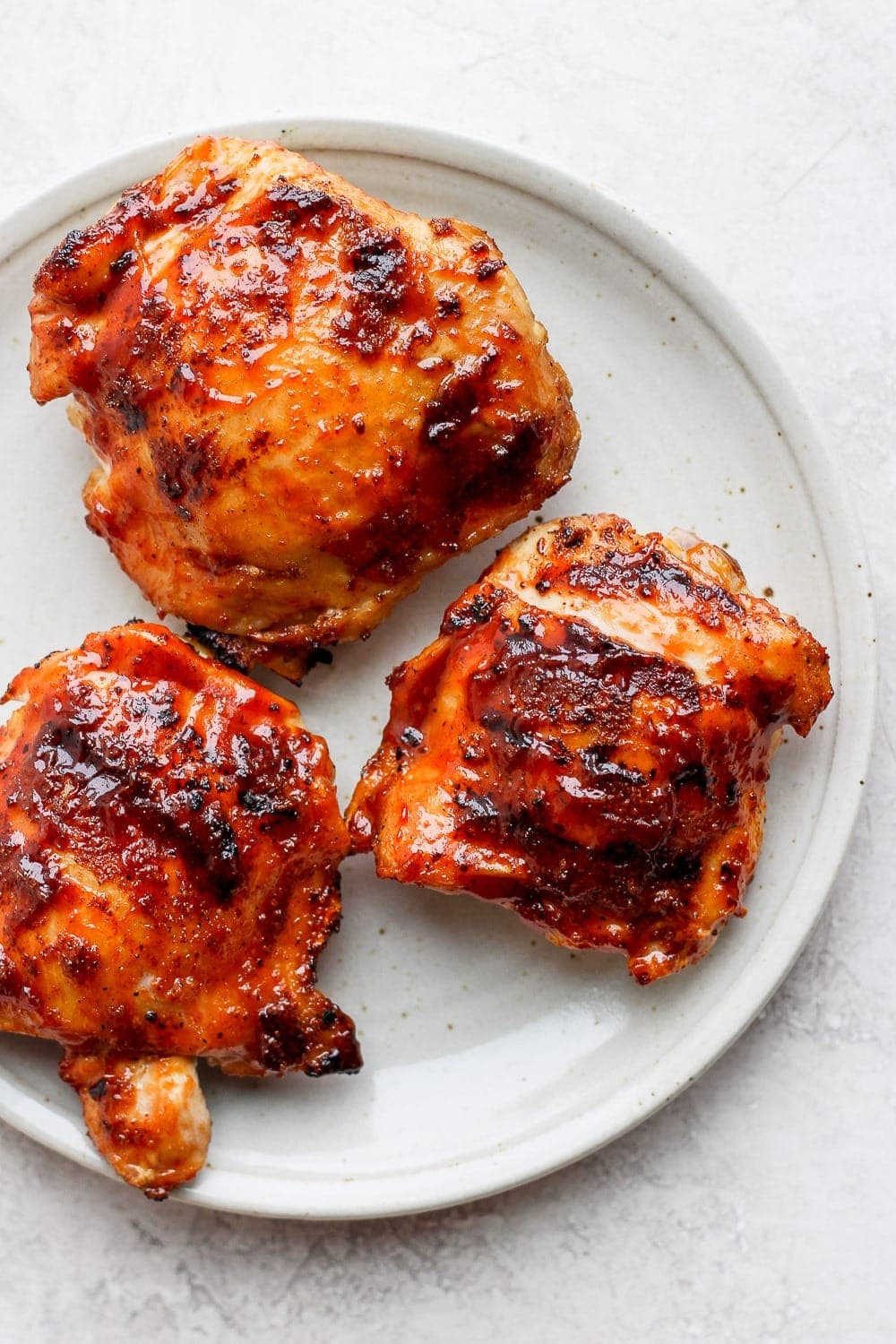 These are truly the best grilled chicken thighs on the internet. They are made with double the flavor thanks to a dry rub and bbq sauce and have perfectly crispy skin with super juicy meat. grilled chicken thighs on plate.
