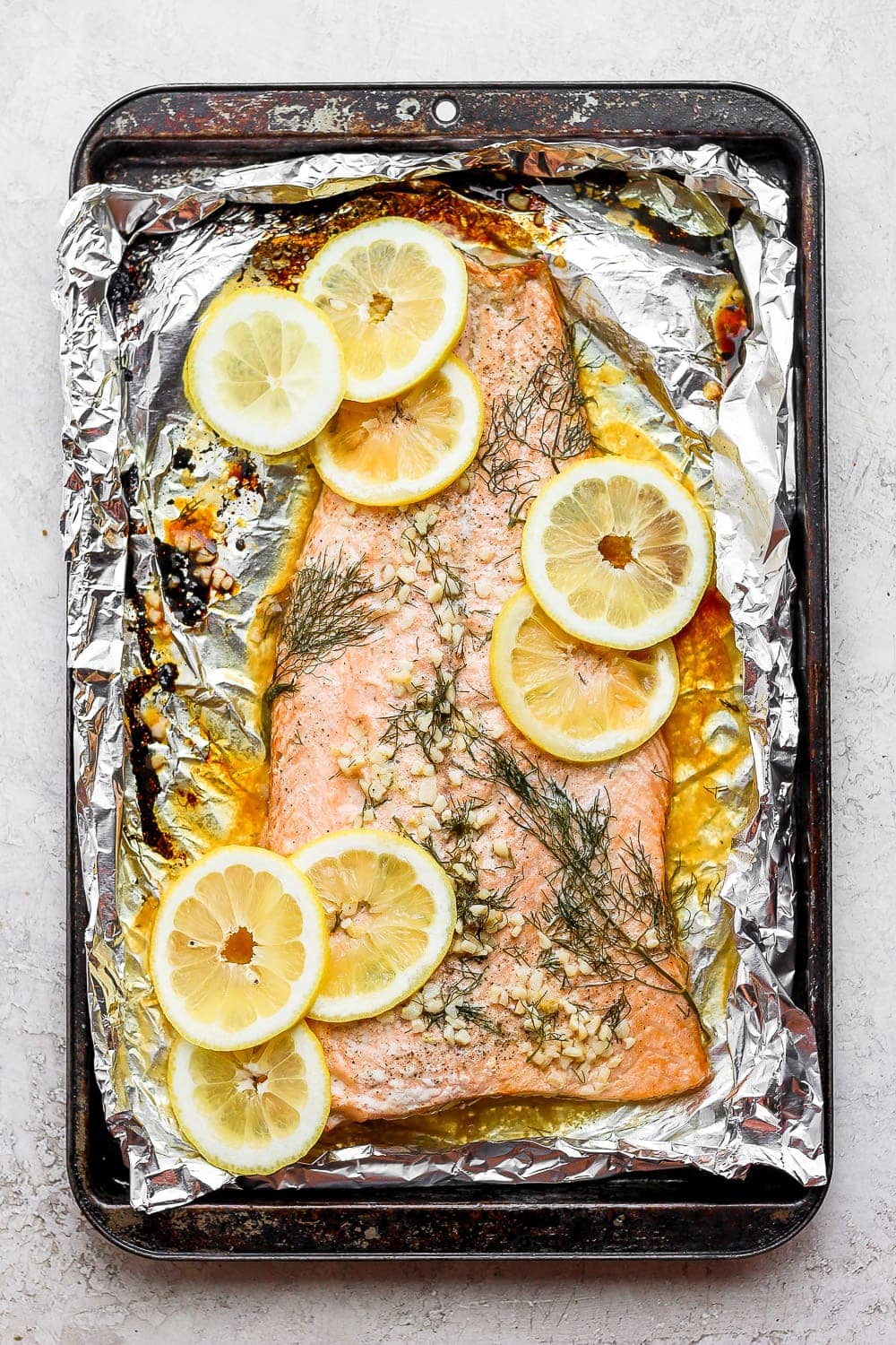 This perfectly cooked oven baked salmon in foil will give your family a delicious, healthy meal! It's naturally gluten-free and high-protein. large salmon fillet on tin foil with lemons