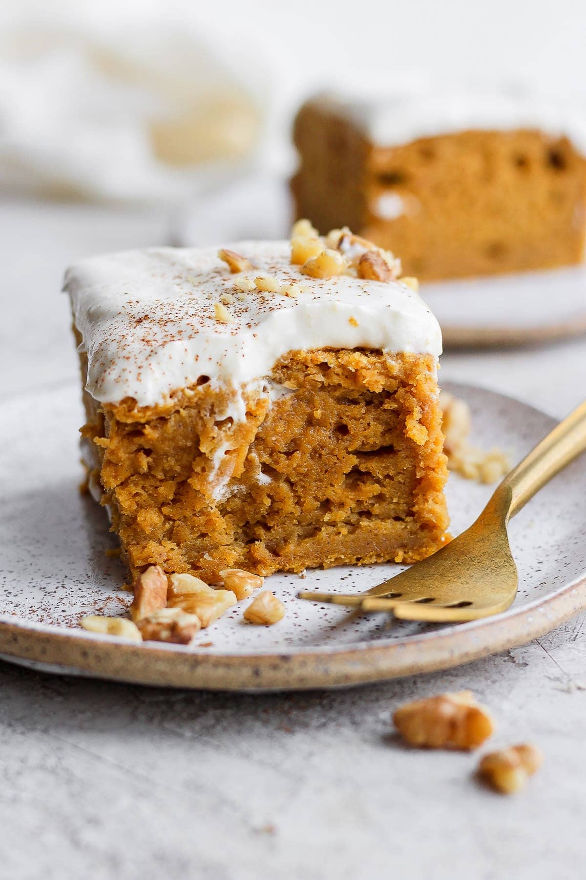 This pumpkin sheet cake is as easy as it is delicious. Packed with simple ingredients and topped with a yummy cream cheese frosting, this dessert can't be beat! slice of pumpkin sheet cake on a plate