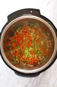 An instant pot filled with chopped veggies.