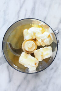 a food processor filled with butter and bananas.