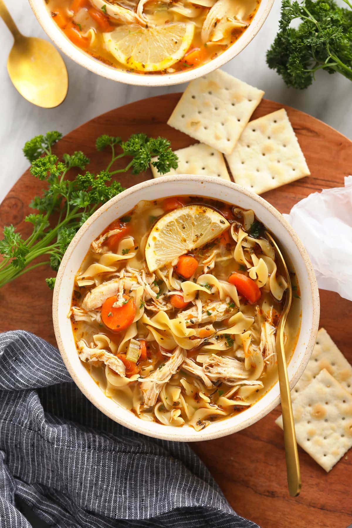 The most flavorful Instant Pot Chicken Noodle Soup made with tons of veggies, tender chicken, egg noodles, and an incredibly tasty broth! chicken noodle soup in bowl with spoon and crackers