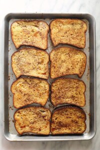 Four slices of french toast on a sheet pan.