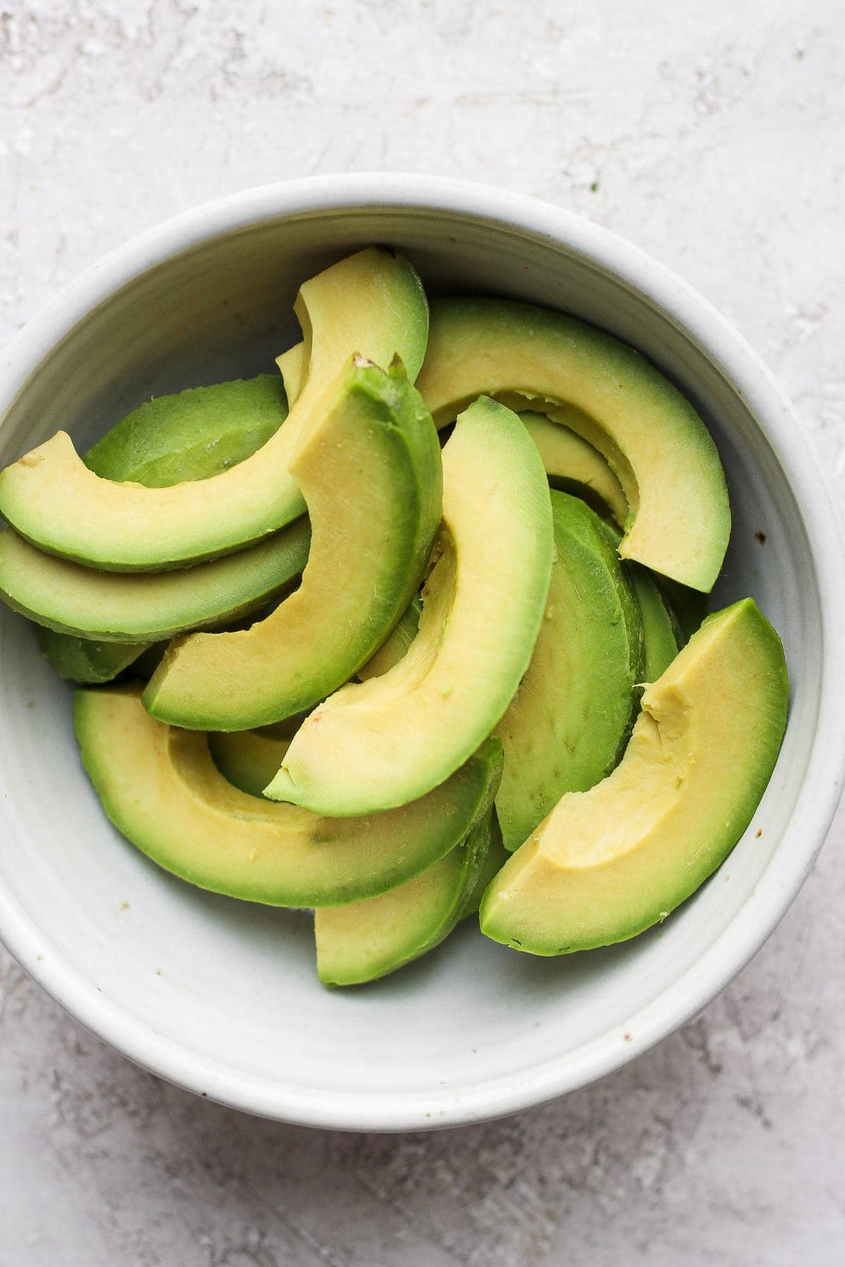 Wondering how to freeze avocados? It's super simple, and we'll show you how! Freeze avocado slices to use later in smoothies, dressings and dips. frozen avocado slices in a bowl