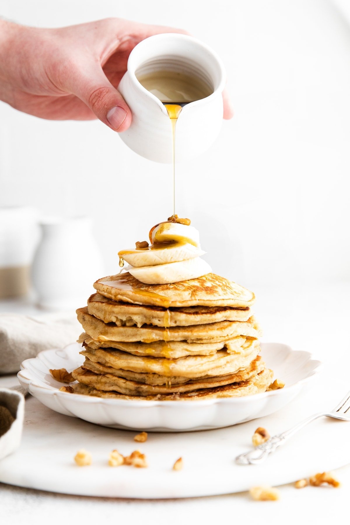 These are seriously the best banana pancakes on the internet! Made with whole grain flour, ripe bananas, and coconut oil, this healthy banana pancake recipe is the perfect weekend breakfast. pouring syrup onto banana pancake recipe