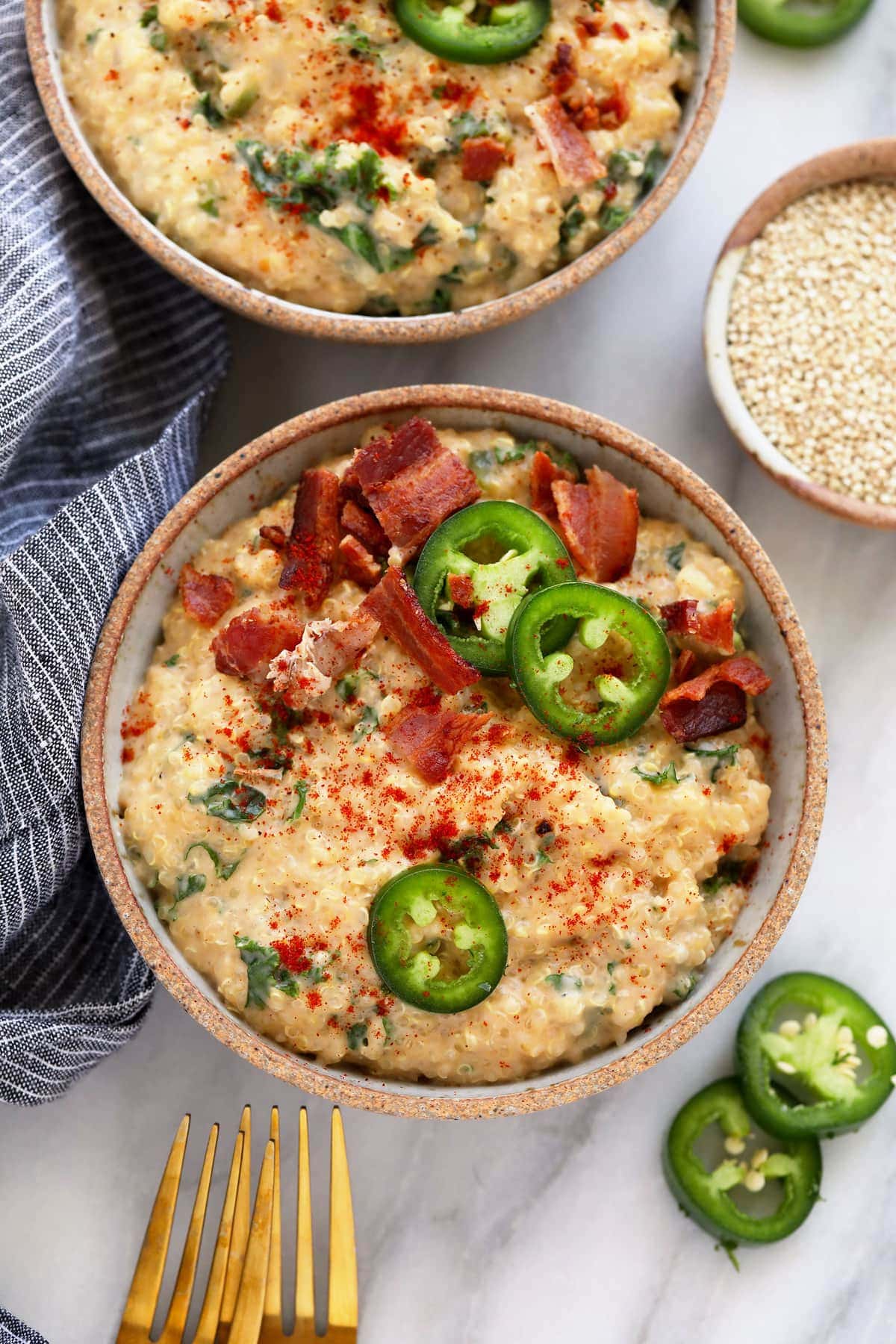 This Jalapeño Bacon Quinoa Mac and Cheese is a delicious twist on a classic. It combines your favorite mac and cheese flavors with jalapeño and bacon and uses quinoa instead of noodles for a gluten-free dish! quinoa mac and cheese in a dish topped with jalapenos and bacon