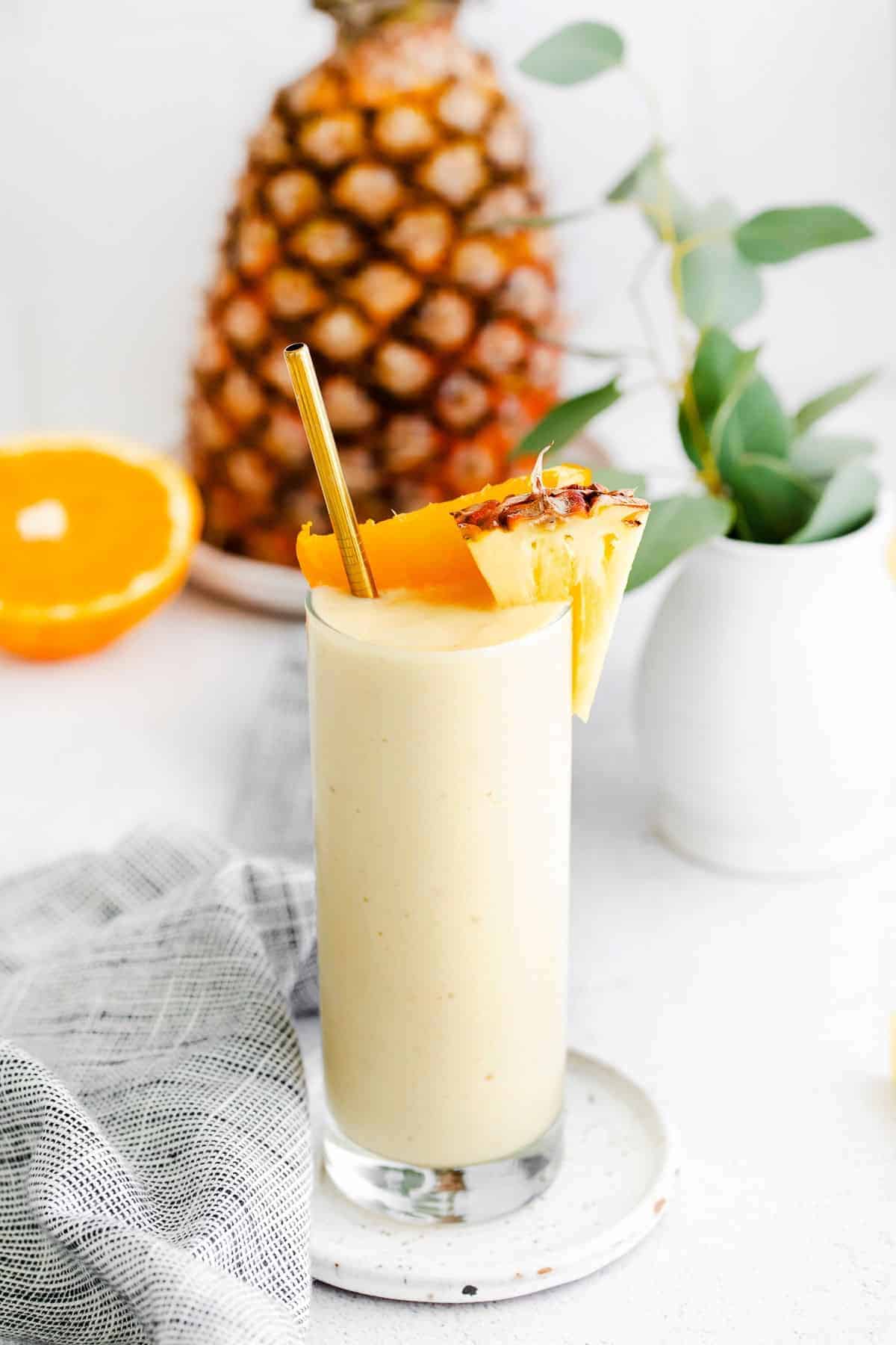 This pineapple smoothie recipe is so refreshing it tastes like vacation. It's made with frozen pineapple, banana, Greek yogurt, and pineapple juice! pineapple smoothie with orange and pineapple chunks