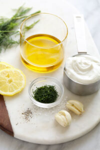 the ingredients for a dill dressing are on a cutting board.