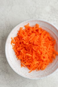 shredded carrots in a white bowl.