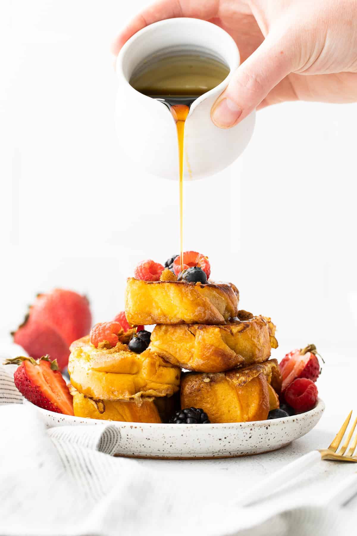 It's time to whip up a batch of the Perfect French Toast. Made from 5 simple ingredients, and ready to enjoy in under 30 minutes. Brunch is served! maple syrup being poured over slices of french toast topped with berries