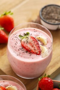 a bowl of strawberry smoothie with chia seeds and strawberries.