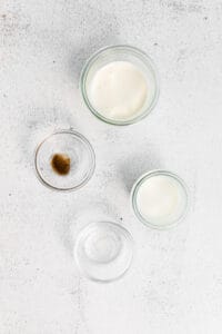 three glass bowls with milk, sugar, and butter on a white background.