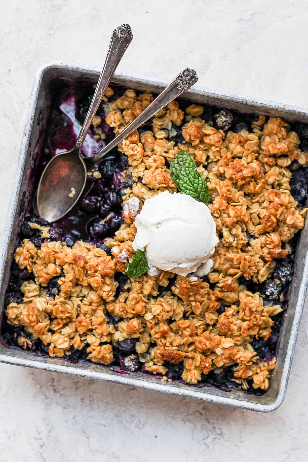 Blueberry crisp in a pan with two spoons.