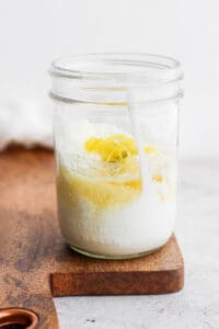 a jar of lemon yogurt on a cutting board.