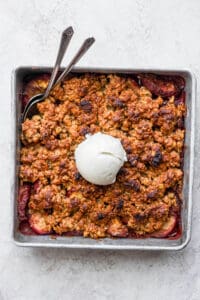 A peach crisp dessert topped with a scoop of ice cream.