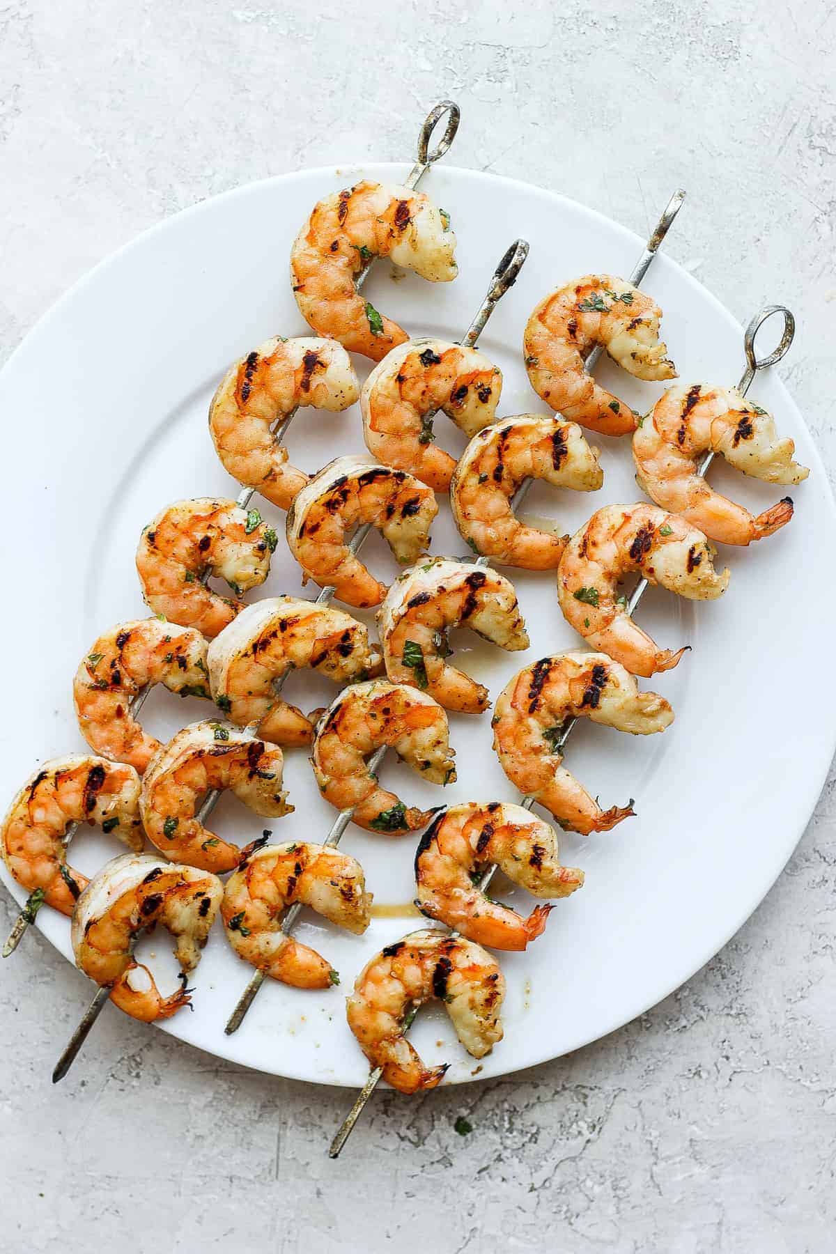 This juicy shrimp marinade adds so much flavor to your shrimp with Worcestershire sauce, garlic, dijon mustard, fresh herbs, and a little citrus. shrimp skewers on plate.