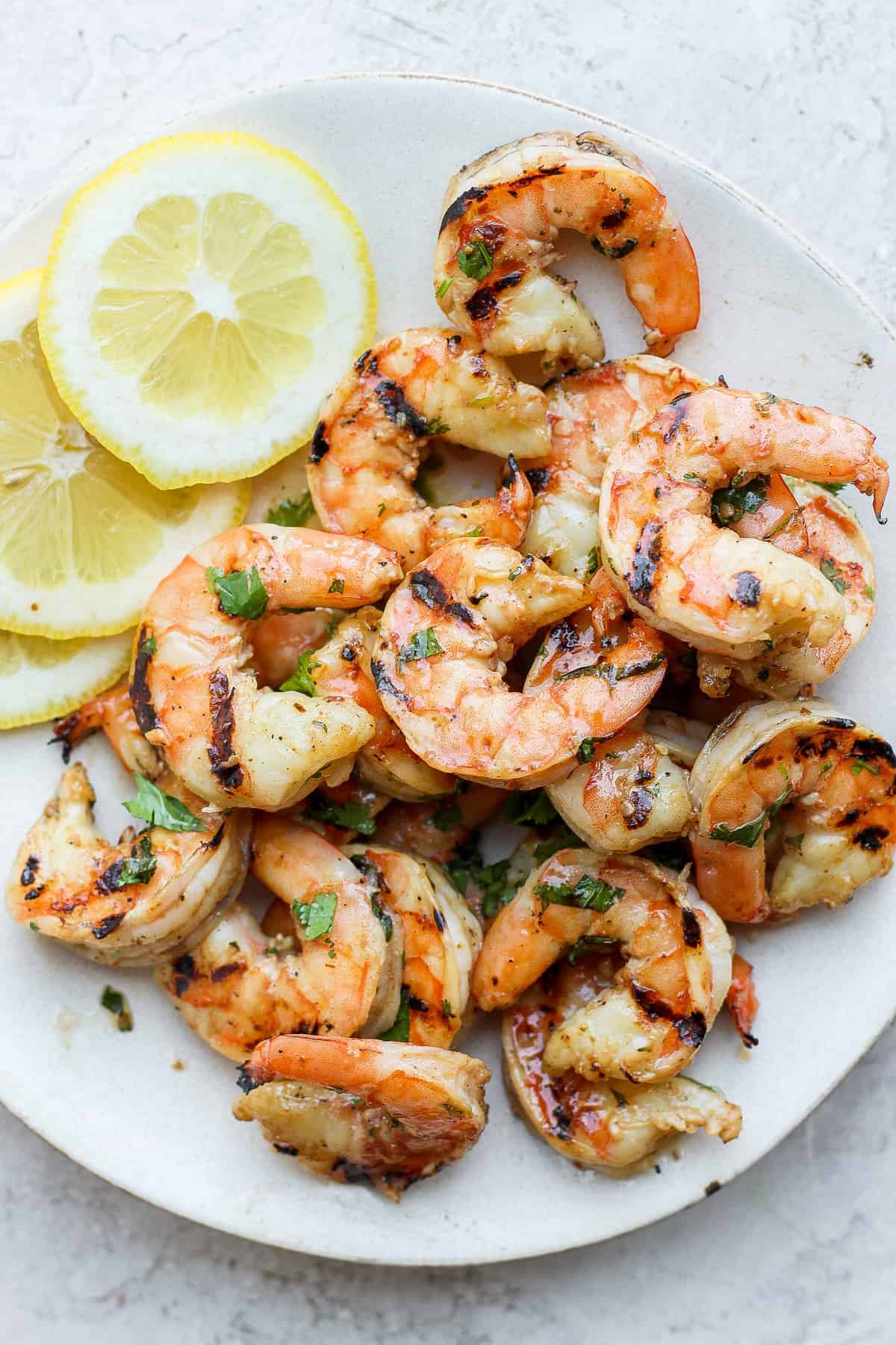 Get perfectly grilled shrimp every single time with this easy and fool-proof step-by-step tutorial on how to grill shrimp! Grilled shrimp on a plate with lemon slices.