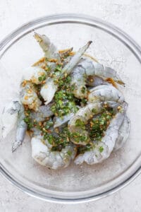 Grilled prawns in a glass bowl with herbs, marinade.